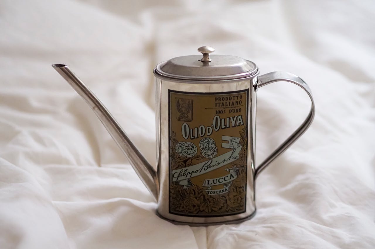 services-02 A vintage olive oil can with Italian labels on a soft, white bed setting.