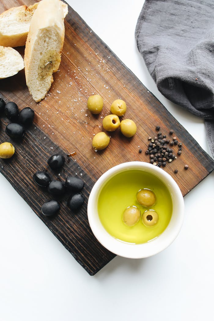 how-it-works Rustic wooden board with fresh olives, bread, and olive oil. Perfect for culinary themes.