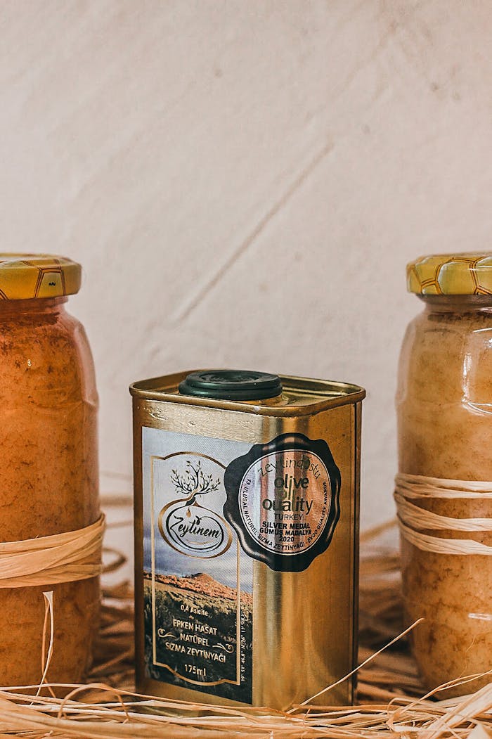 The Art of Drawing Readers In: Your attractive post title goes here A still life product shot featuring olive oil in a can and honey in glass jars set on a wicker mat.